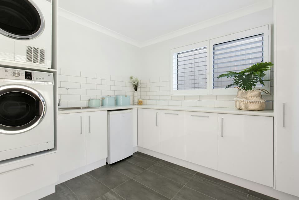 A white home laundry room with a dryer stacked above a front-loading washer